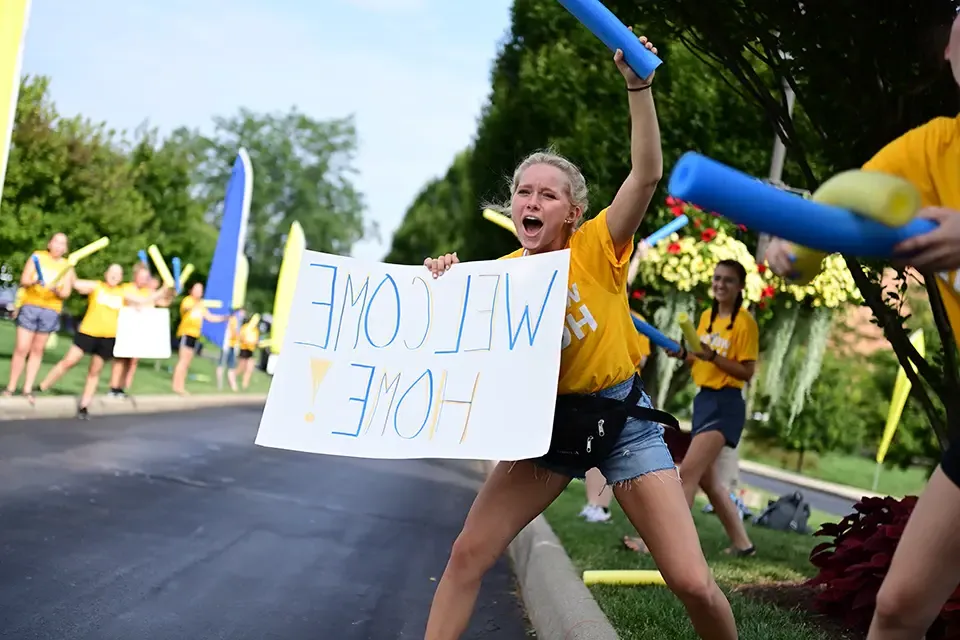 Girl yelling and holding welcome home sign